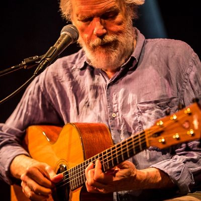Picture of Leo Kottke standing and playing his guitar