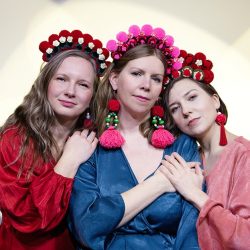 three women dressed in blue, pink and red, wearing Polish flowered tiaras