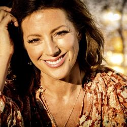 Sarah McLachlan with smile, fingers brushing her hair back