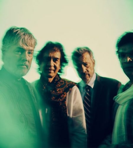 Bela Fleck Zakir Hussain Edgard Meyer and Rakesh Chaurasia standing next to each other. The picture is slightly blurred
